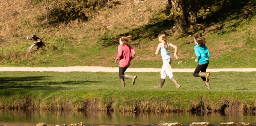 Children running along the river bank at Dovedale