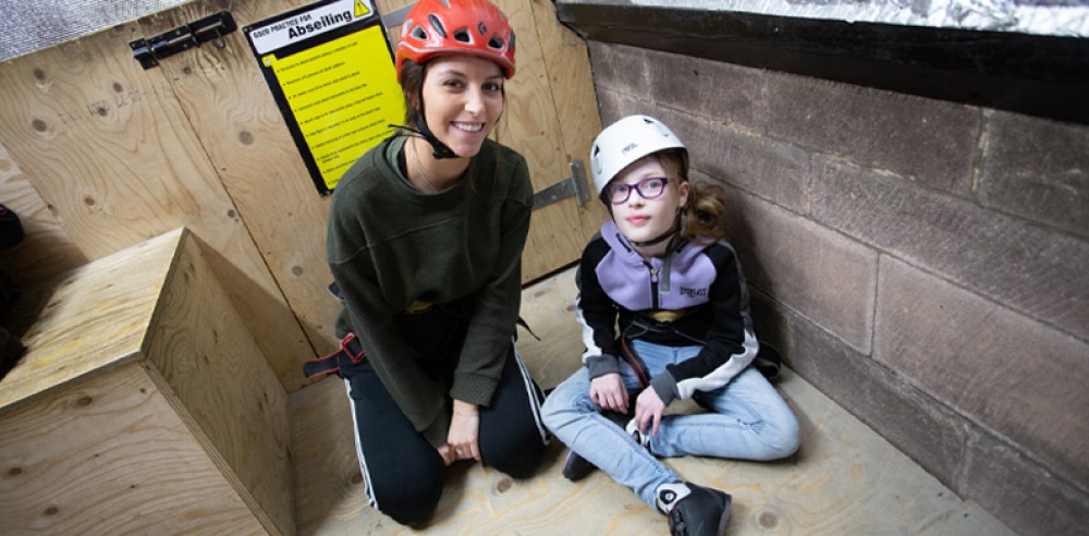 Volunteer with a child at the rock climbing centre